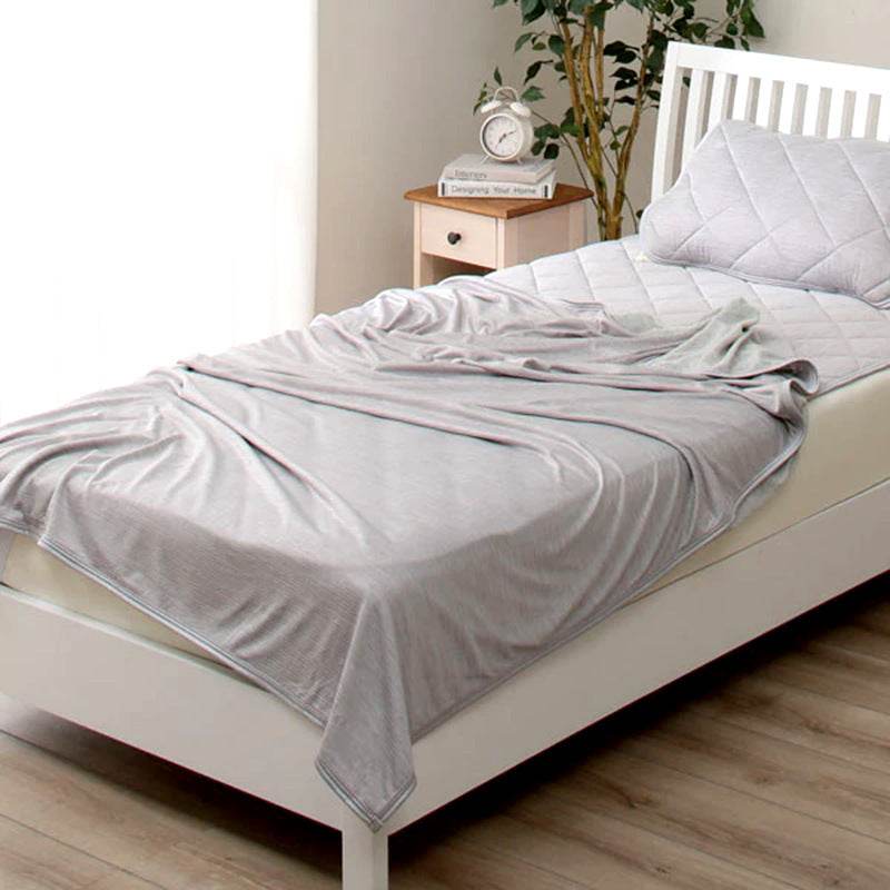 Light grey summer cooling blanket on bed with pillow, designed with advanced Japanese cooling fibers for heat relief.