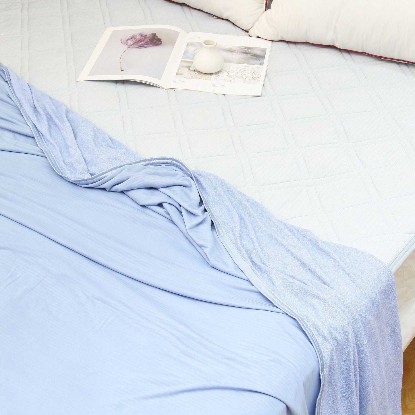 Lightweight summer cooling blanket with advanced Japanese Q-Max fibers on a bed.