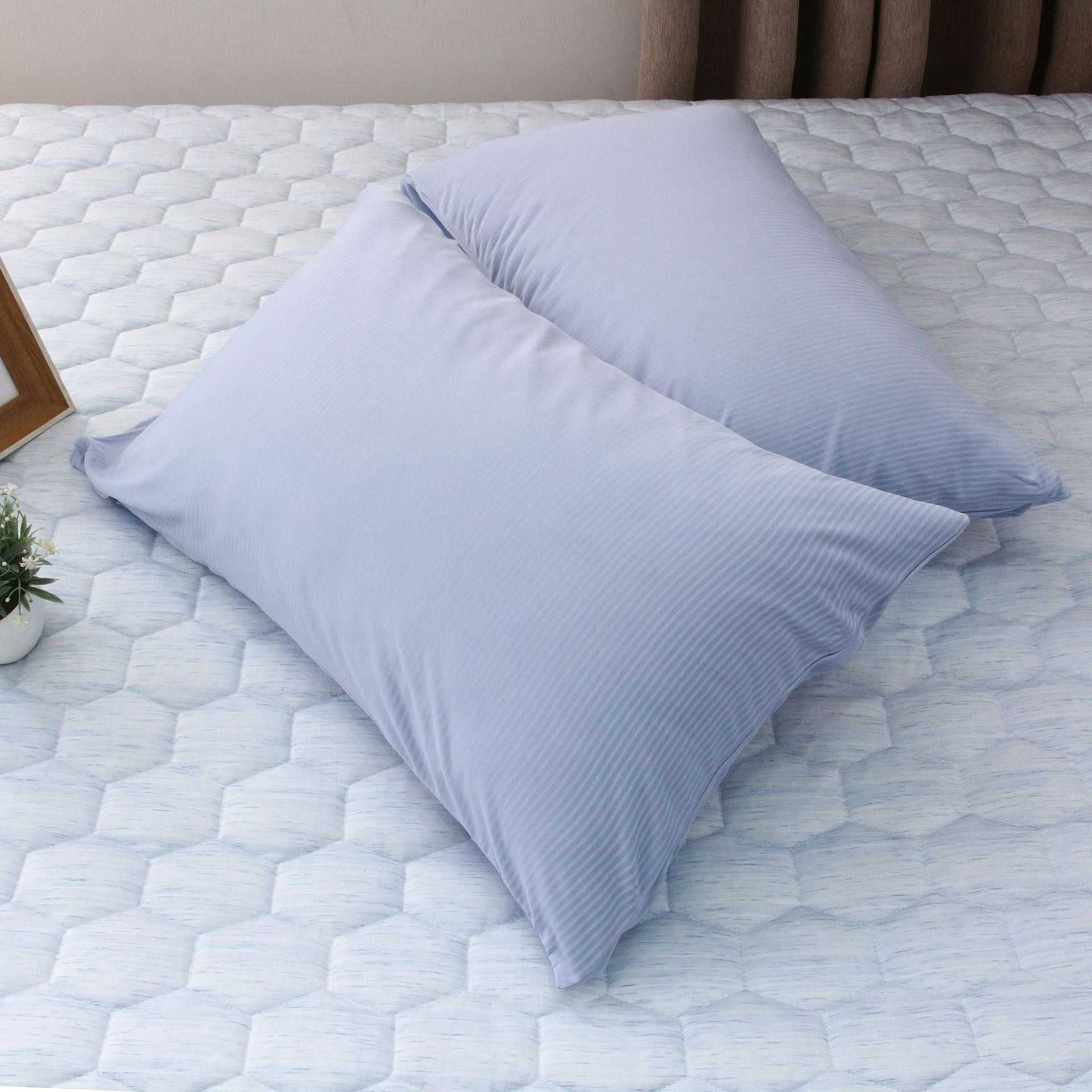Light blue summer cooling blanket and pillow on a mattress.