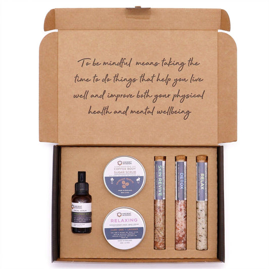 Mindful Moments Self Care Kit featuring body scrub, body cream, bath salts, and hyaluronic acid serum for relaxation and rejuvenation.