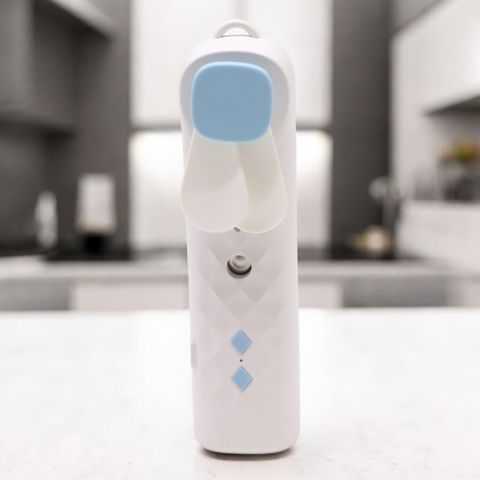 White USB rechargeable nano mist face fan with cooling blades and minimalist design on kitchen counter