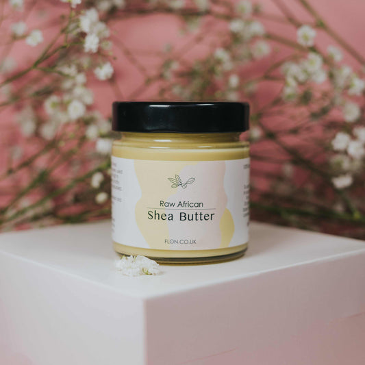 FLON Raw Unrefined African Shea Butter in reusable glass jar with natural floral background.