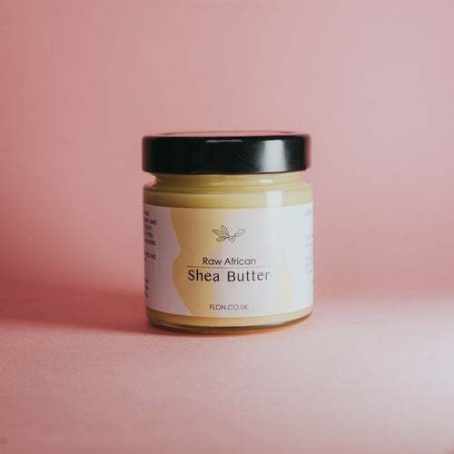 FLON Raw Unrefined African Shea Butter in reusable glass jar with natural floral background.