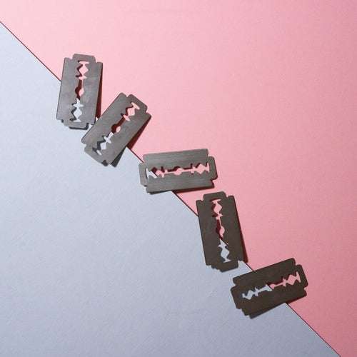FLON Safety Razor Blades, stainless steel, double edge, floating against a pink background.
