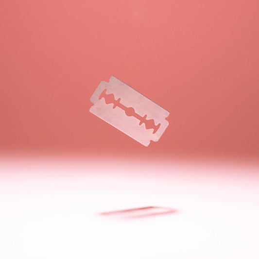 FLON Safety Razor Blades, stainless steel, double edge, floating against a pink background.