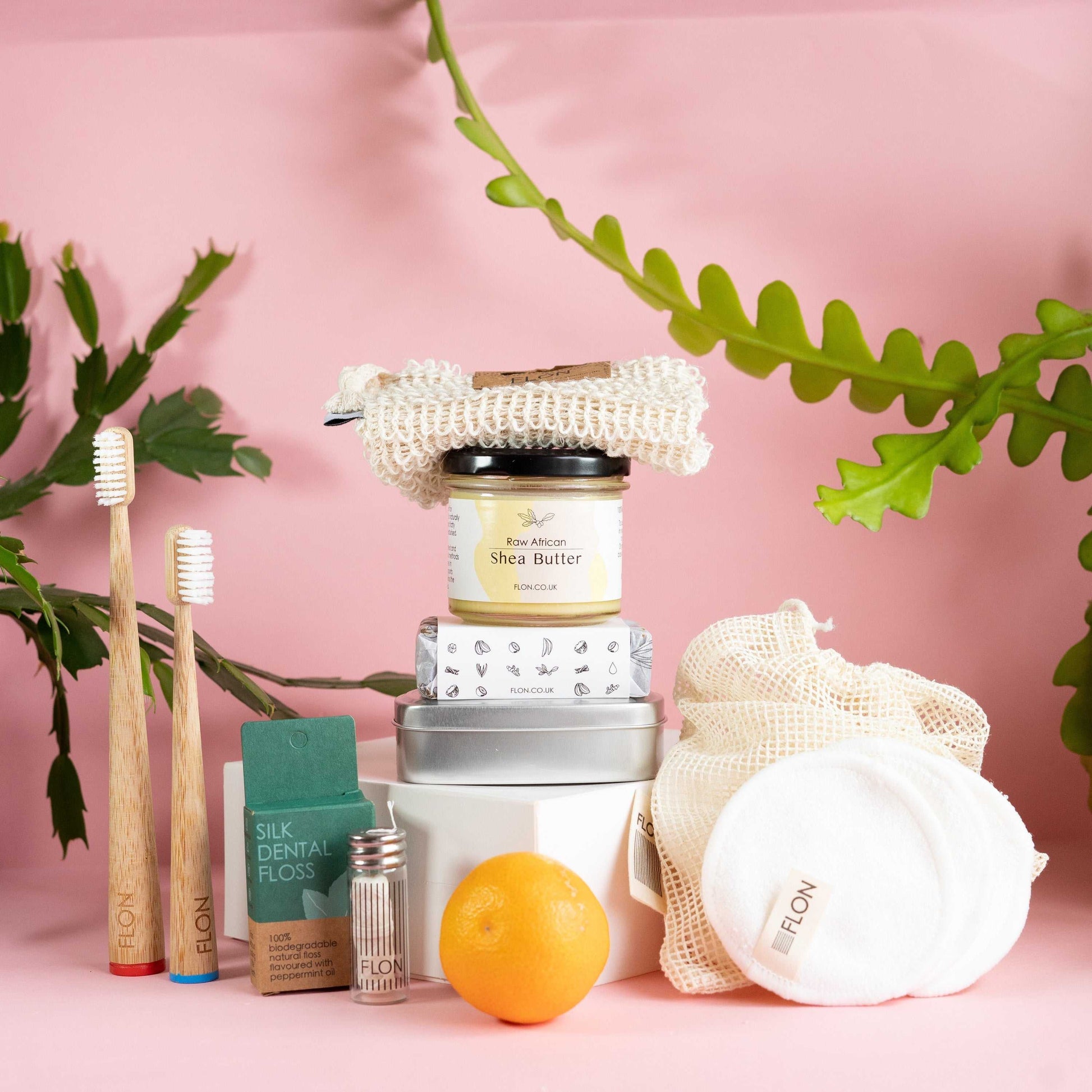 Eco Bathroom Gift Set with bamboo toothbrushes, shea butter, African black soap, sisal washcloth, silk floss, and reusable bamboo pads, offering natural, low-waste essentials.