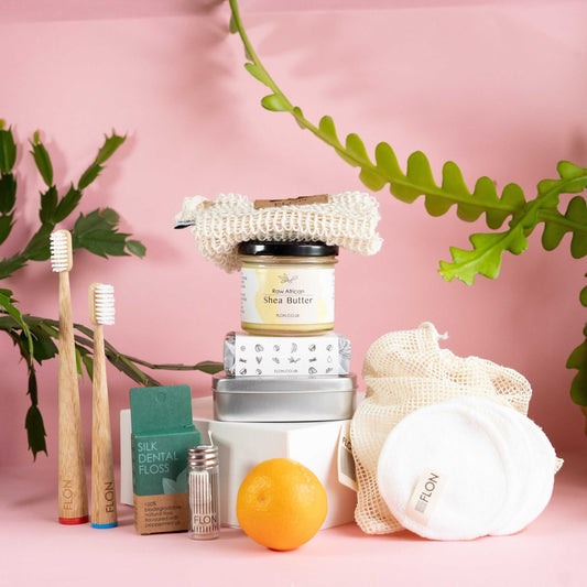 Eco Bathroom Gift Set with bamboo toothbrushes, shea butter, African black soap, sisal washcloth, silk floss, and reusable bamboo pads, offering natural, low-waste essentials.
