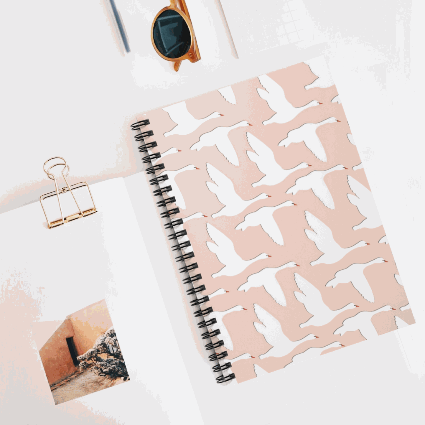 Swans Flying notebook with pink cover and black spiral binding.